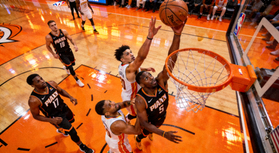 NBA焦点战役中球员在场上激烈拼抢的瞬间，橙色灯光映照球场